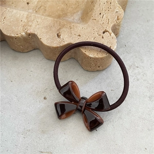 Macro shot of dark brown acetate bow hair tie on a natural stone base