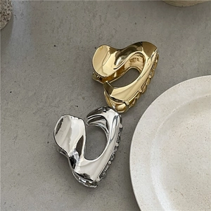 Pinze per capelli minimaliste in metallo liquido argento e oro su sfondo strutturato