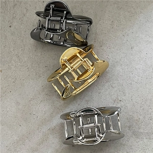 Vista dettagliata di tre fermagli per capelli in metallo nei colori nero, oro e argento