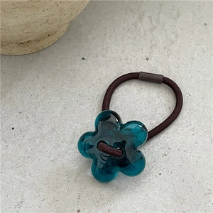 Détail d'un élastique à fleurs en acrylique bleu avec une cordelette élastique marron