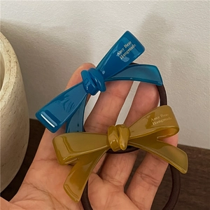 Vue à la main d'élastiques à cheveux avec nœuds en acétate bleu marine et vert olive