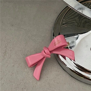 Détail de la pince à cheveux nœud en acétate rose avec finition polie et clip doré