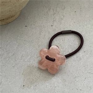 Détail d'un chouchou fleur en acrylique rose clair avec cordon élastique marron café