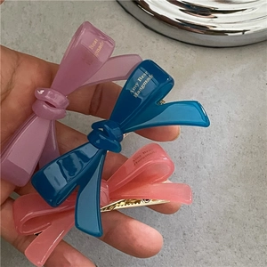 Trois barrettes nœuds en acétate violet, bleu et rose avec logo doré et pince crocodile