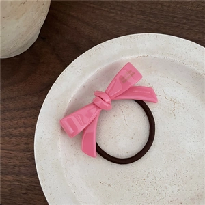 Détail d'un chouchou rose en acétate avec nœud et lettrage fait main sur assiette