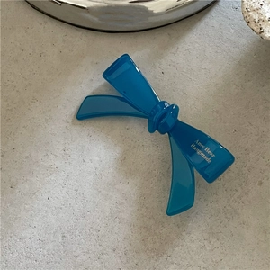 Détail d'une pince à cheveux nœud en acétate bleu foncé avec lettrage blanc élégant