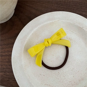 Détail d'un chouchou noeud en acétate jaune avec texte Amy Bear Handmade sur assiette