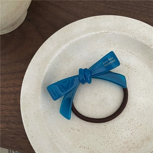 Détail chouchou nœud en acétate bleu avec lettrage doré sur une assiette en céramique