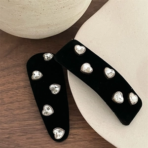 Elegant black velvet BB hair clips with crystal heart detailing on a wooden surface