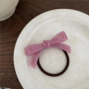 Gros plan d'un chouchou noeud en acétate rose avec lettrage doré sur une assiette blanche