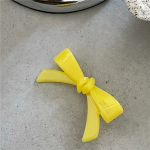 Gros plan détaillé d'une barrette à cheveux nœud en acétate jaune avec surface polie et nœud 3D