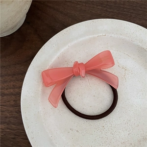 Vue macro détaillée d'un chouchou noeud en acétate rose corail sur un plat en céramique