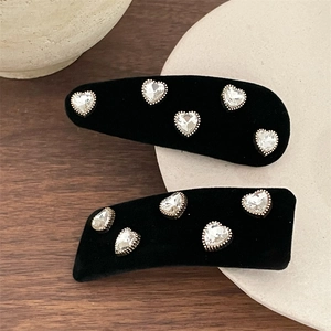 Close-up of black velvet hair clips featuring five sparkling heart-shaped rhinestones