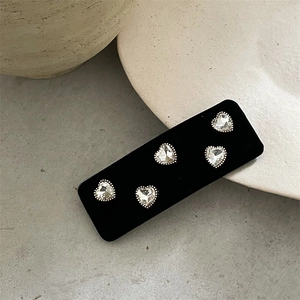 Detailed view of heart-shaped rhinestone earrings on a premium black velvet card