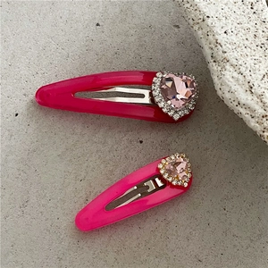 Détail de barrettes à cheveux coeur rose néon avec cristaux brillants sur fond de pierre