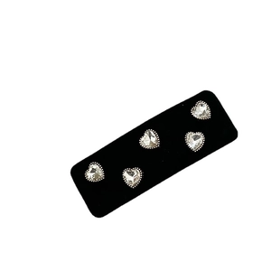 Five-piece heart crystal clips on black velvet board with silver beaded metal edges
