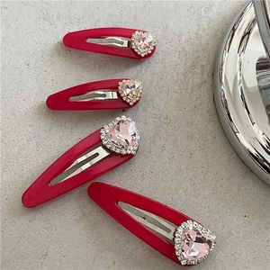 Détail de quatre barrettes rouges avec strass en forme de cœur rose et micro-cristaux