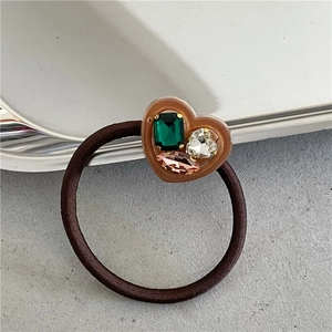 Detailed macro view of heart-shaped resin hair tie with colorful inlaid rhinestones