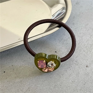 Close-up of green heart-shaped resin hair tie with pink and white rhinestones