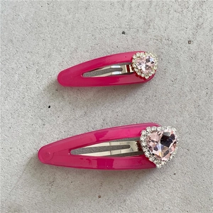 Détail de barrettes à cheveux rose rouge avec cristaux de cœur roses et pierres brillantes