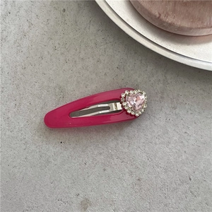 Détail d'une pince à cheveux cœur en cristal rose avec petits diamants sur base en métal