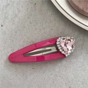 Détail de la pince à cheveux avec cœur rose en pierre précieuse et bordure de strass