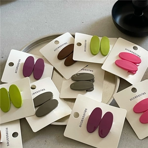 Colorful oval matte duckbill hair clips for women on a grey ceramic tray showcase