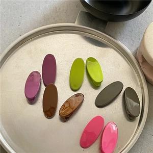 Colorful oval hair clips in a silver tray with minimalist marble and pottery decor