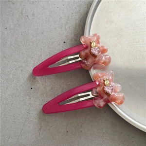 Détail de barrettes ours rose en résine marbrée avec cristal en forme de cœur rose
