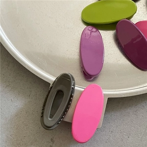 Detail view of colorful oval snap hair clips in glossy finish displayed on a metal tray