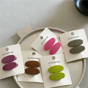 Close-up of five pairs of colorful oval resin hair clips on display cards in a metal tray