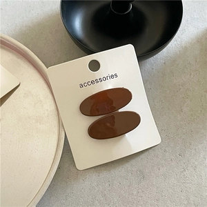Detail view of coffee brown oval resin hair clips on a white accessories card