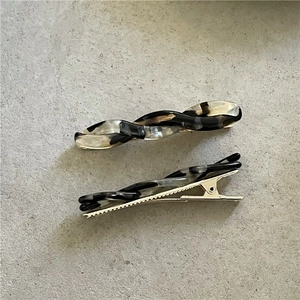 Detail view of acetate twist hair clips with marble texture and gold metal duckbill base