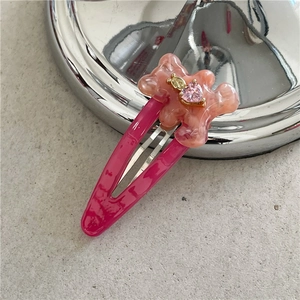 Détail d'une pince à cheveux ours rose avec gemme en cœur sur barrette goutte d'eau