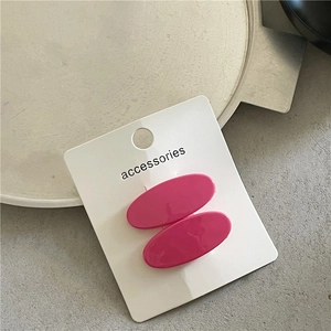 Detail of pink oval resin hair clips on a white display card with glossy smooth texture
