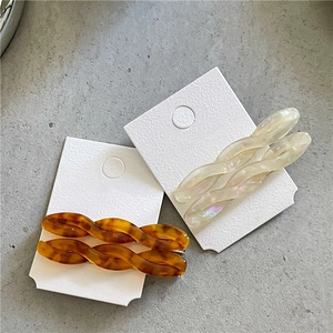 Detail view of acetate twisted hair clips in amber tortoiseshell and aurora white finishes