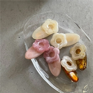 Set of 6 cute floral hair clips in cream, pink, and amber on a sleek glass tray