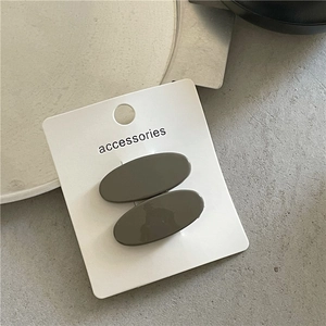 Macro detail of glossy olive green oval hair clips on an accessories display card