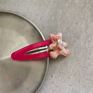 Détail d'une pince à cheveux ours marbré rose avec gemme coeur sur plateau