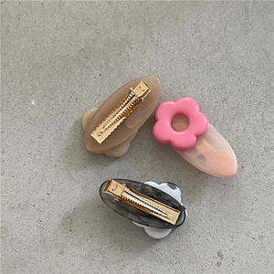 Three cute floral and marble hair clips in pink and beige on a grey stone texture background