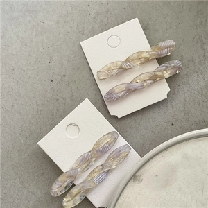 Close-up of four marble texture acetate twist hair clips in purple and amber colors