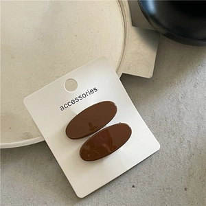 Close-up of dual dark coffee oval hair clips on an accessories display card