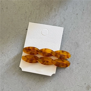 Detailed macro view of two amber acetate twist hair clips on white display card