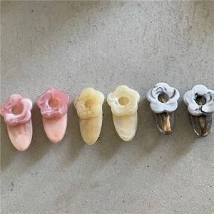 Detailed close-up of marble pattern resin flower hair clips in pink, yellow and black colors