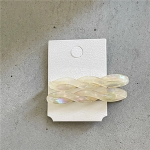 Close-up of elegant iridescent twist hair clips with a pearlescent finish on a card