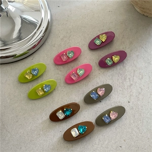 Détail de pinces à cheveux ovales aux couleurs bonbon avec strass cœur et rectangle
