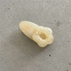 Detail of a pale yellow floral hair clip with a smooth cream-like resin finish