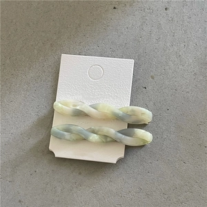 Detail view of twisted marble acetate hair clips in pastel tones on a white card