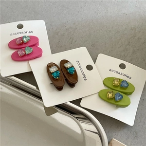 Détail de barrettes ovales colorées avec strass en cœur sur une carte de présentation