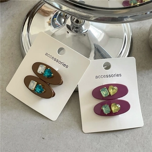 Détail de barrettes ovales colorées avec strass incrustés et cristaux en forme de cœur